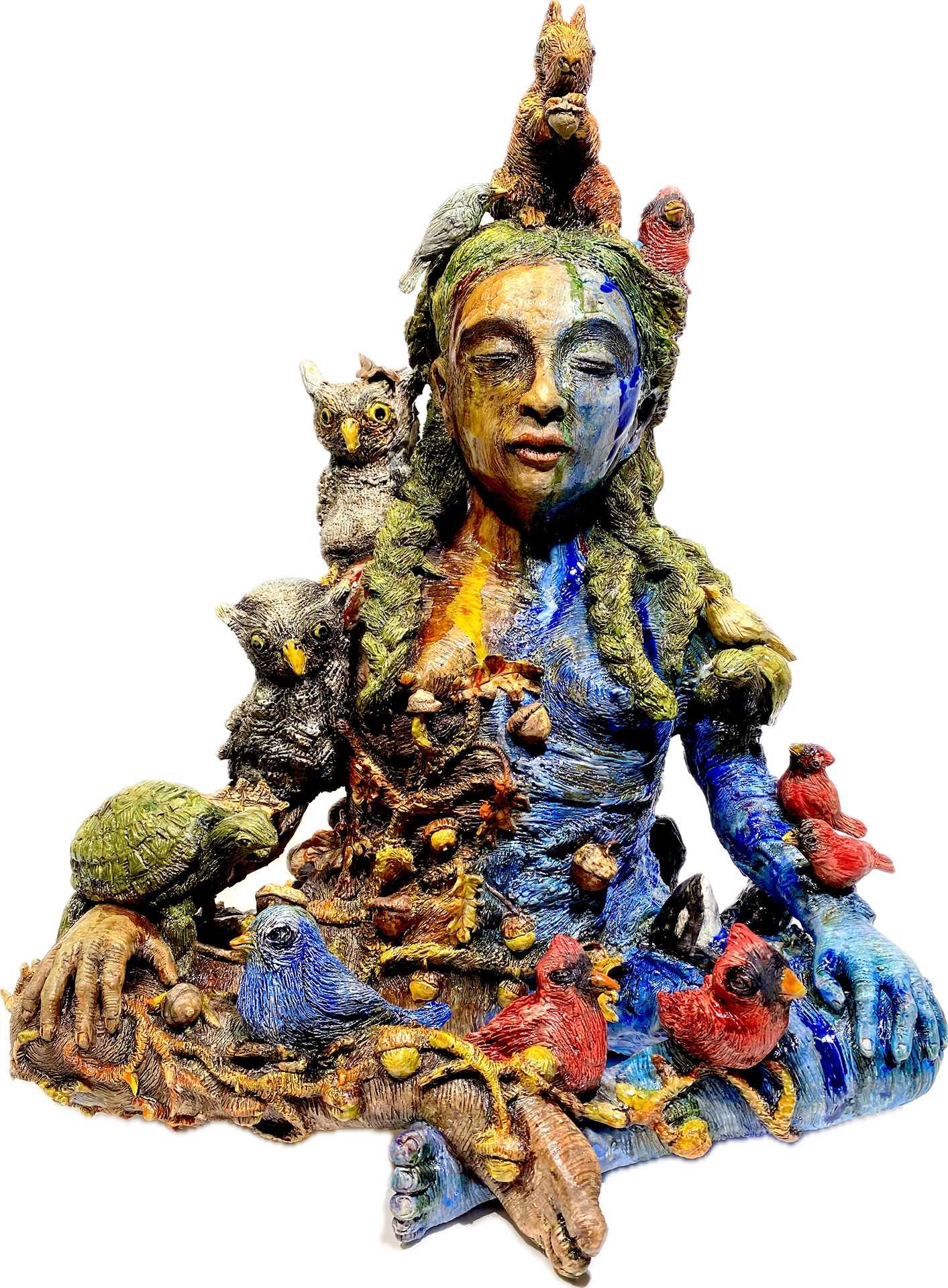 a multicolor ceramic sculpture of a woman sitting cross legged with birds and small mammals sitting on and around her. 