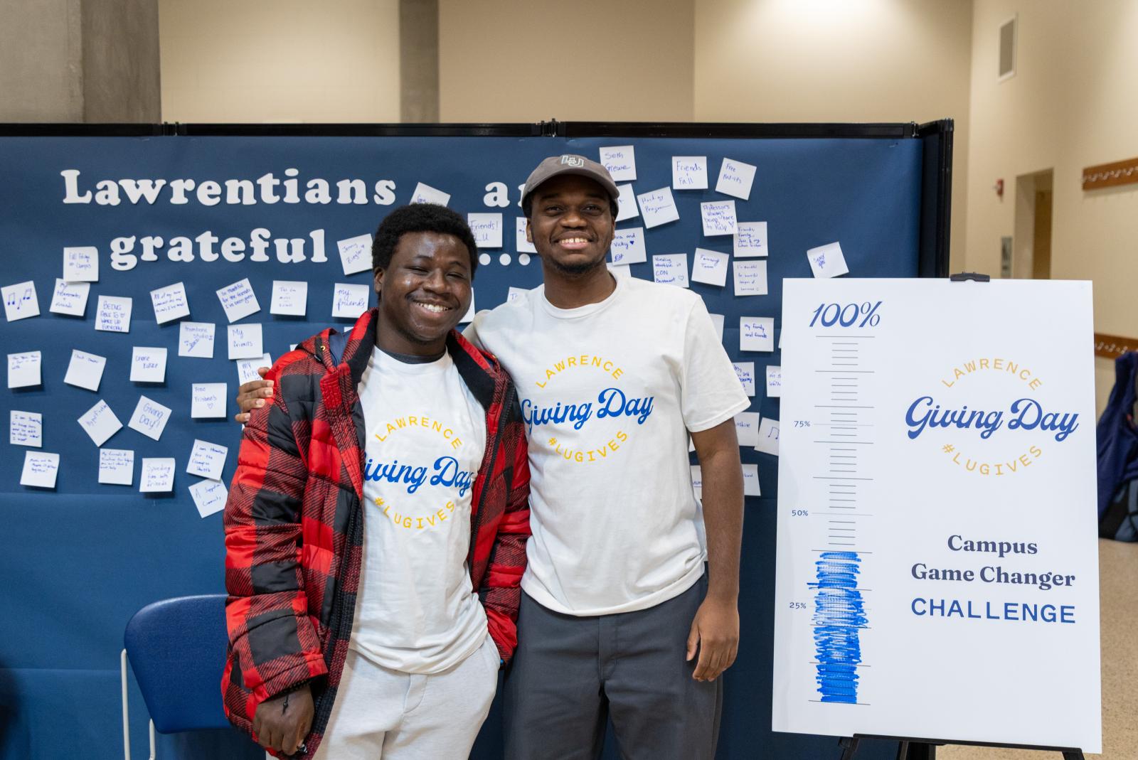 Two students stand by the Gratitude Board on Giving Day