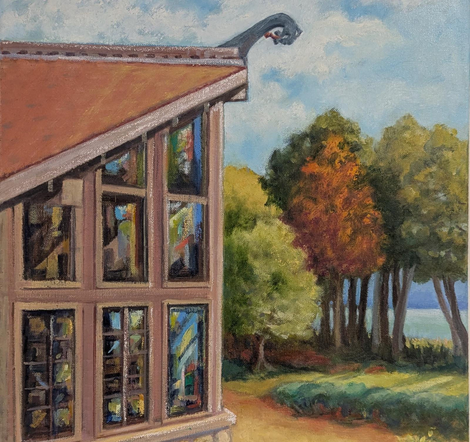 A view of Bjorklunden's 'Great Room' from the outside. The image points north and depicts the iconic windowed corner of the room in the foreground. Behind it sit autumn trees with leaves of oange, green, and gold. And behind them sit white cumulus clouds in a blue sky, suspended above the seemingly endless water of Lake Michigan.