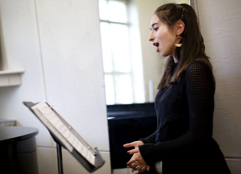 Emily Austin looks at sheet music on a music stand as she sings.