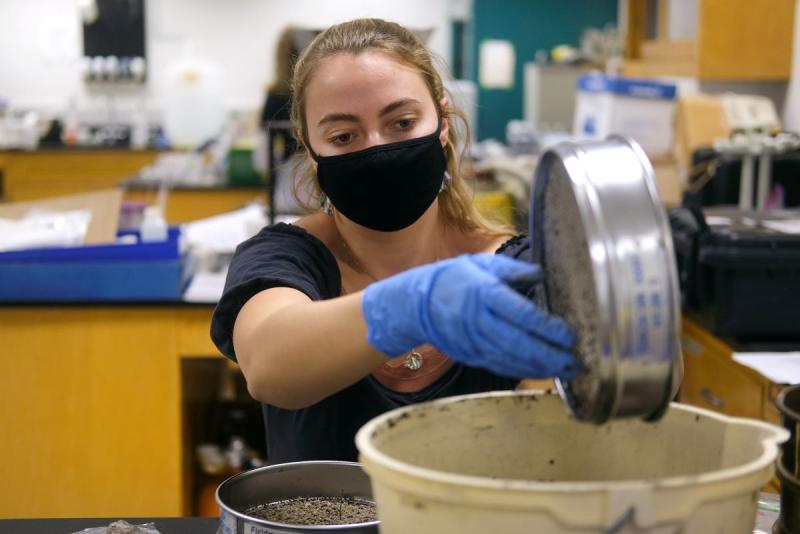 student sifting soil in a lab 