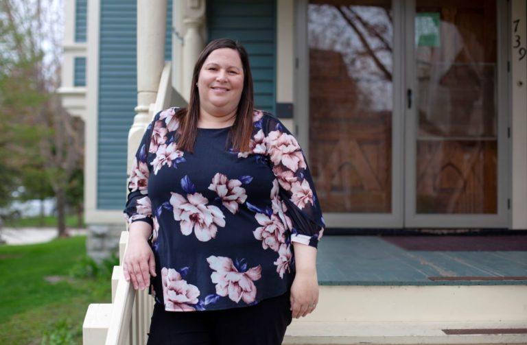 Lezlie Weber, wearing a floral shirt and leaning on a railing, smiles at the camera.