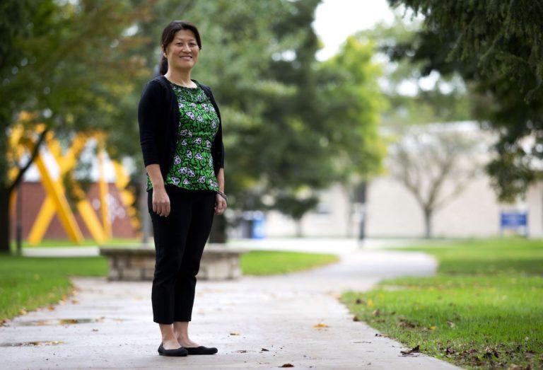 Dominica Chang, wearing a green shirt, stands on Main Hall Green.