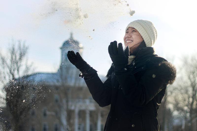 Student tosses snow in the air in front of Main Hall