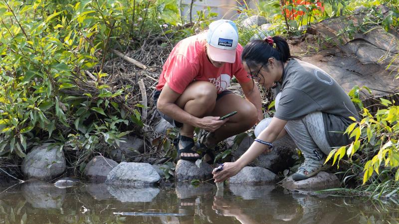 Student and faculty member conduct research by a river