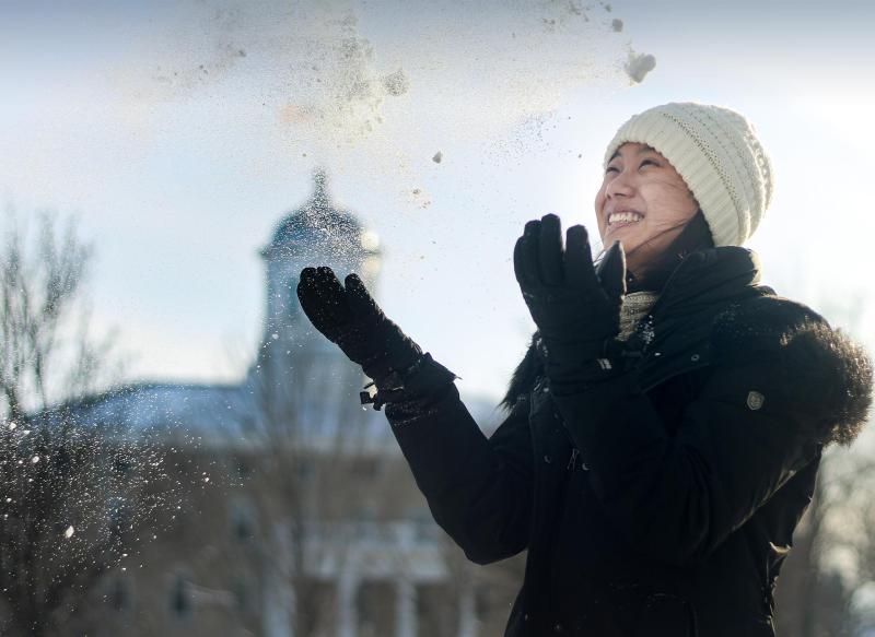 Student tosses snow into air in front of Main Hall