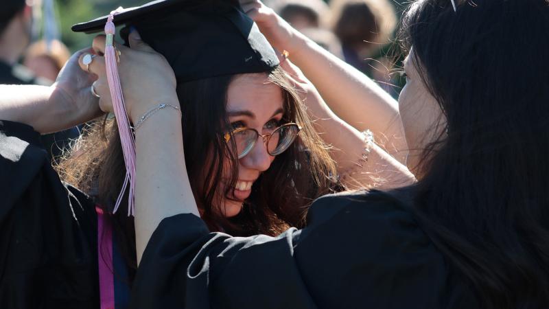 Graduate placing mortar board on head