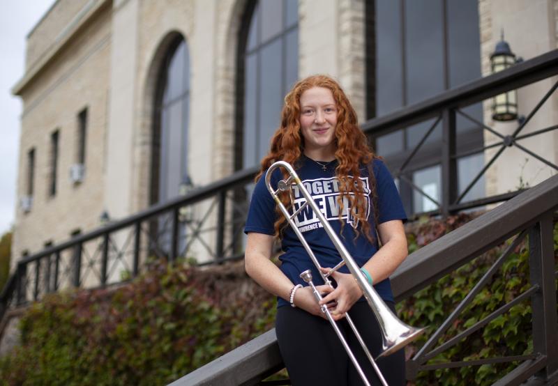Mallory Meyer, wearing a Lawrence T-shirt, holds her trombone.