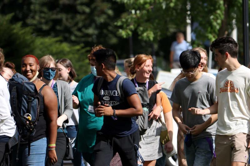 Large group of new students walking and chatting with one another.