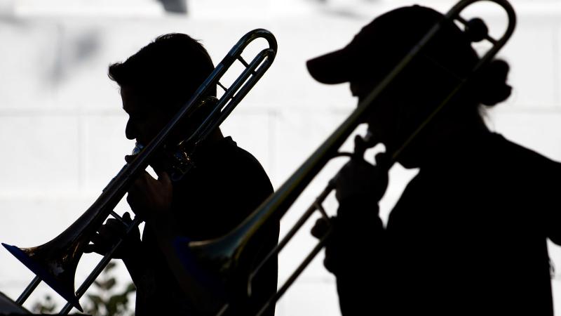 Silhouettes of trombone players outdoors