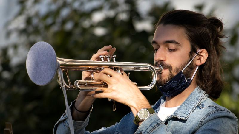 Student plays trumpet outdoors