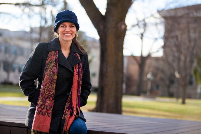 Allison Fleshman, wearing a blue hat and red scarf, smiles at the camera.