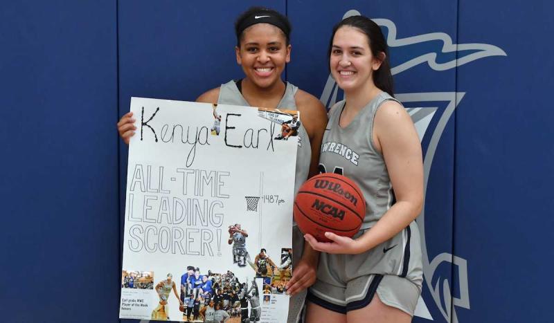 Kenya Earl stands with Karina Herrera while holding a handmade sign that says All Time Leading Scorer.