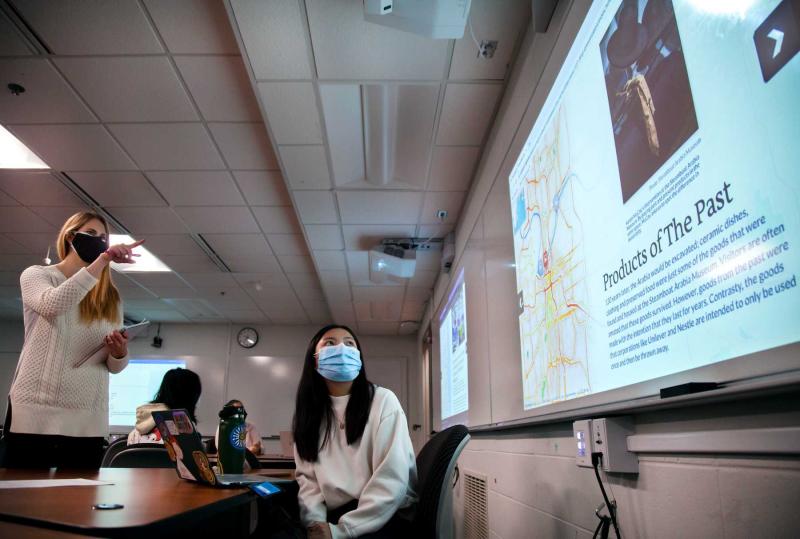 Professor Claire Kervin points at a large screen as she talks with student Juli Clarkson about her work in Environmental Justice and Citizenship.