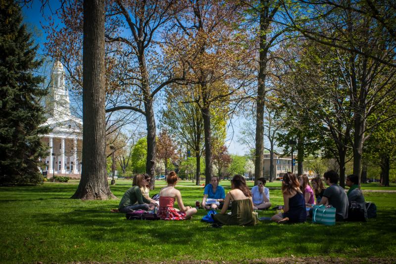 A philosophy class sits in a circle on the grass of Main Hall Green as Ingrid Albrach teaches. Memorial Chapel is in the background.