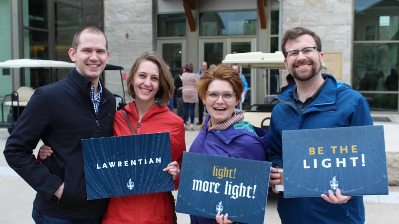 Reunion 2019, alumni are holding signs that read, "Lawrentian" and "Light! More Light!" and "Be the Light!"