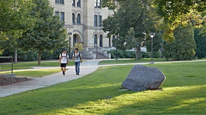 Students walking across Main Hall Green by the Rock