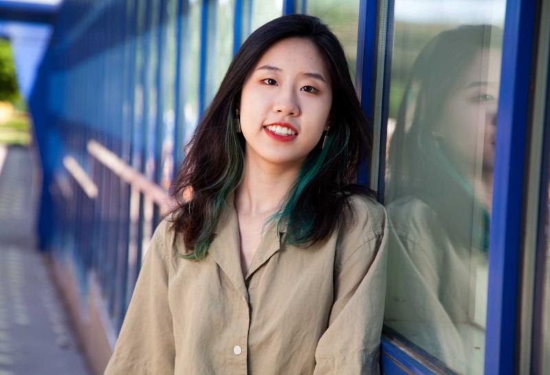 Jin Han leans against a window of the Wriston Art Center.