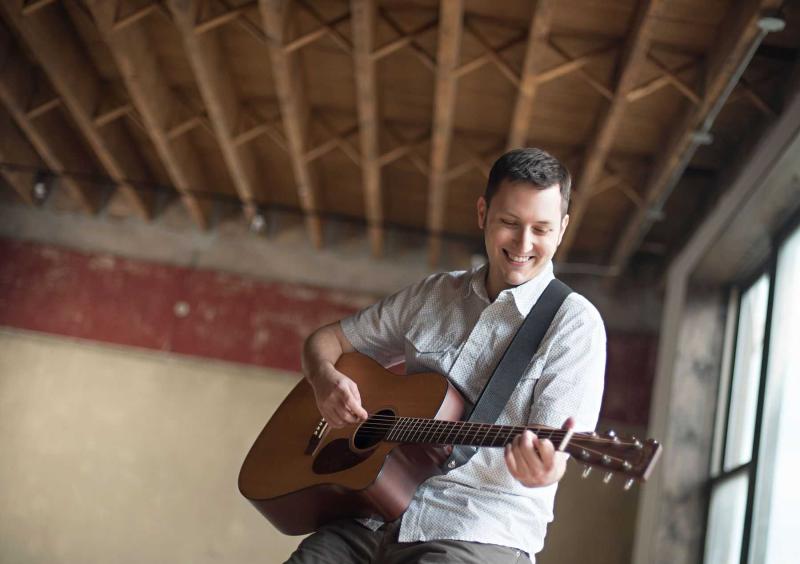 Portrait of Zachary Scot Johnson playing a guitar.