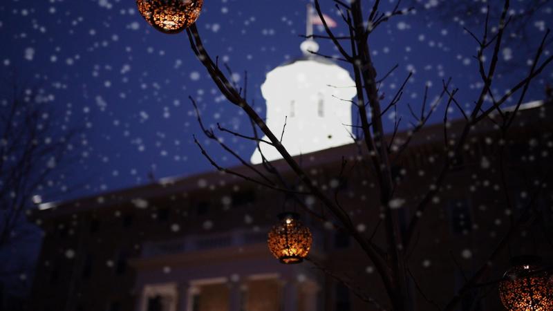 Lawrence Main Hall at night with snow and lanterns