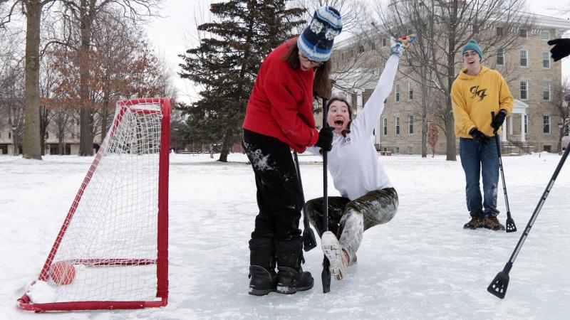 Student falling in front of a goalie as they score a goal at the Winter Carnival Broomball Event