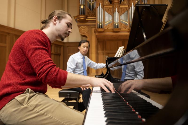 Bohdan Tataryn practices on the piano as Anthony Padilla offers instruction.