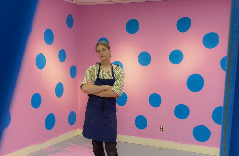 Charlie Wetzel poses for a photo in the middle of a pink and blue art installation.
