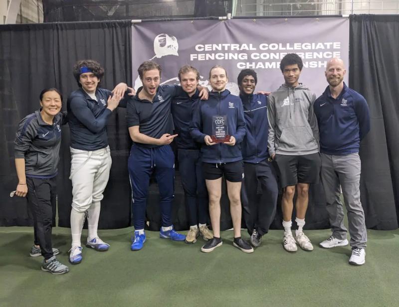 Saber athletes and coach Eric Momberg show the championship trophy.