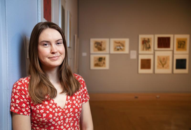Sarah Matthews poses for a photo amid her art exhibit in Wriston Art Galleries.