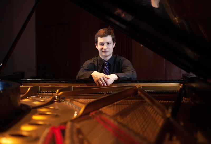 Jonathan Bass poses for a portrait with a piano in the Music-Drama Center.