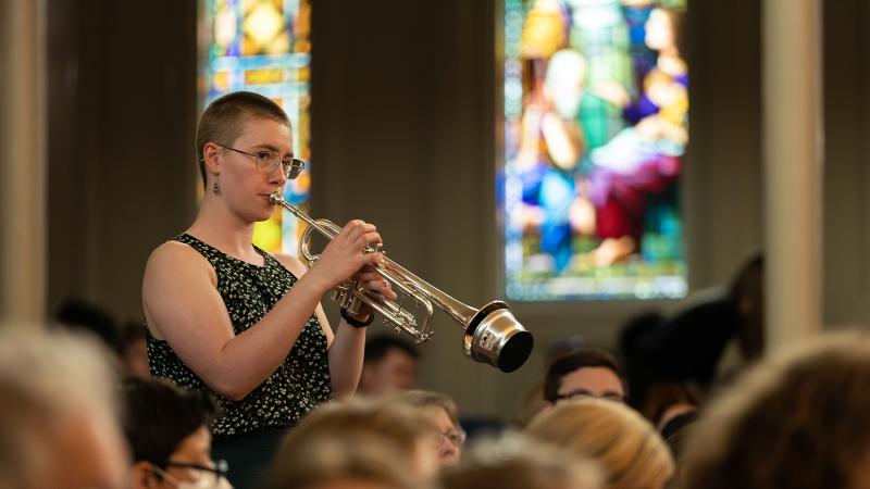 Student plays muted trumpet in Lawrence Chapel during Baccalaureate service