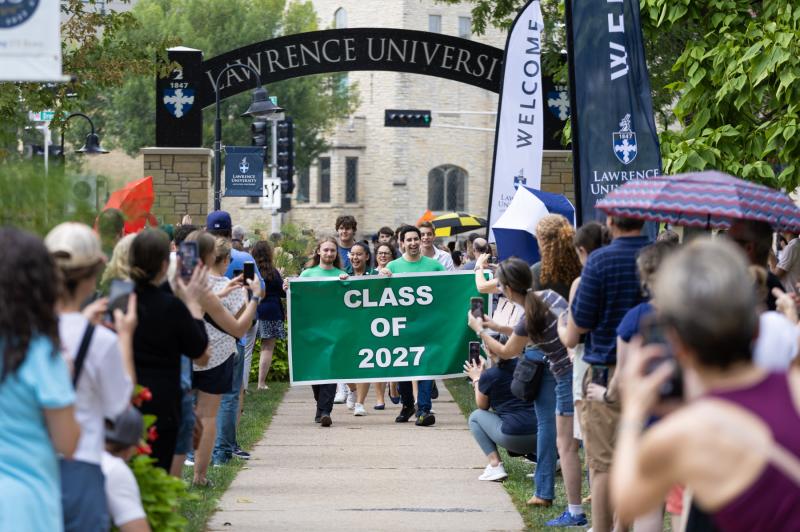 Members of the Class of 2027 hold their green class banner as they walk beneath the Lawrence Arch on their way to the President's Welcome.