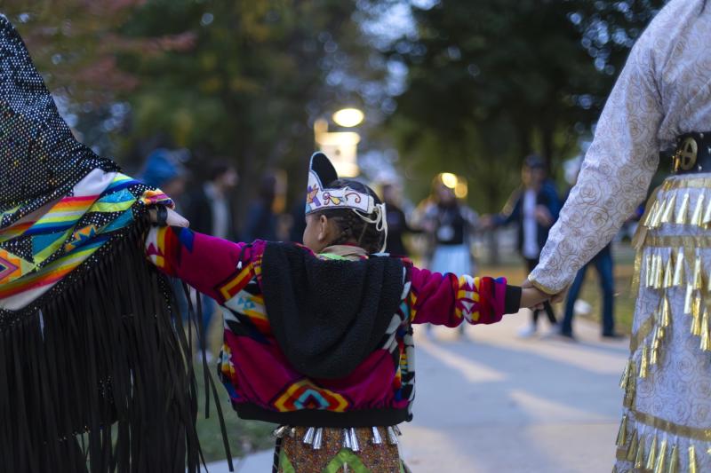 A child holds hands with other participants during the Indigenous Peoples' Day Celebration on Main Hall Green.