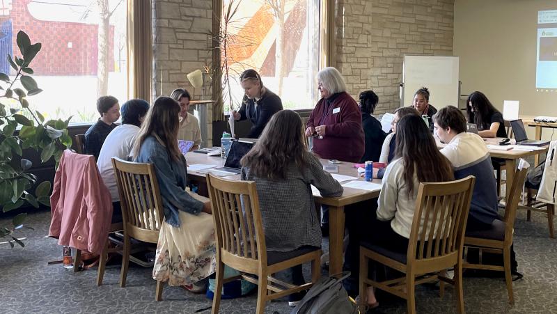 Librarian working with students near windows in the library.