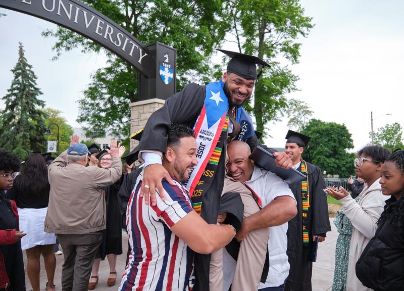Jose Otero, a neuroscience major from New York, gets a left from supporters as he walks through the Lawrence Arch following Commencement.