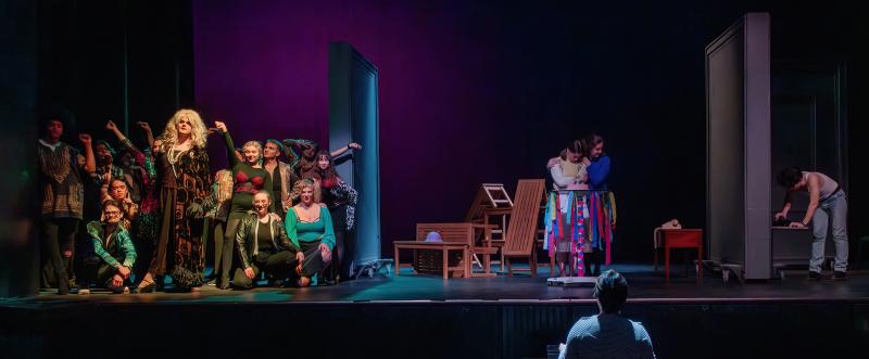 An ensemble of costumed performers on a stage divided into three sections.