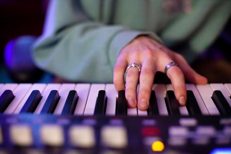 A close-up shot of a hand playing an electric keyboard.
