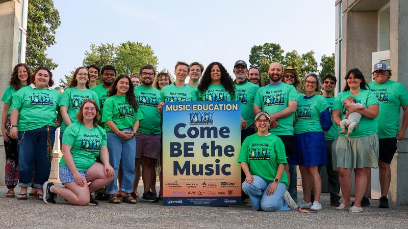 The Mile of Music's Music Education Team group photo, with a poster that reads "Come BE the Music".