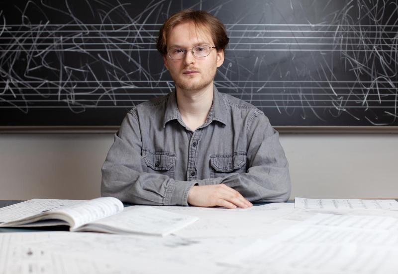 Brock Daumler with musical scores scattered on table in front of him
