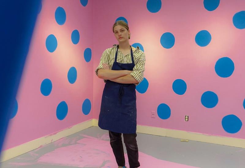 Charlie Wetzel poses for a photo in the middle of a pink and blue art installation.