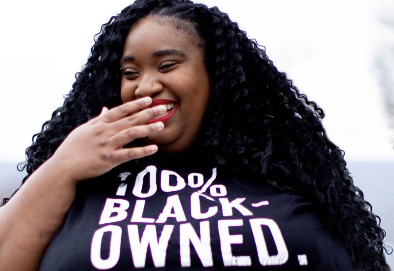Brienne Colston laughing and in a 100% Black-Owned tshirt