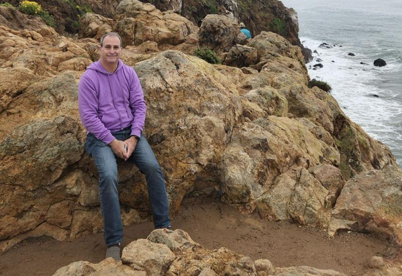 Tod Gimbel on rock cliff side by the water