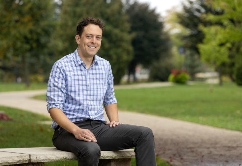 Graham Sazama sits on a bench outside of Main Hall.