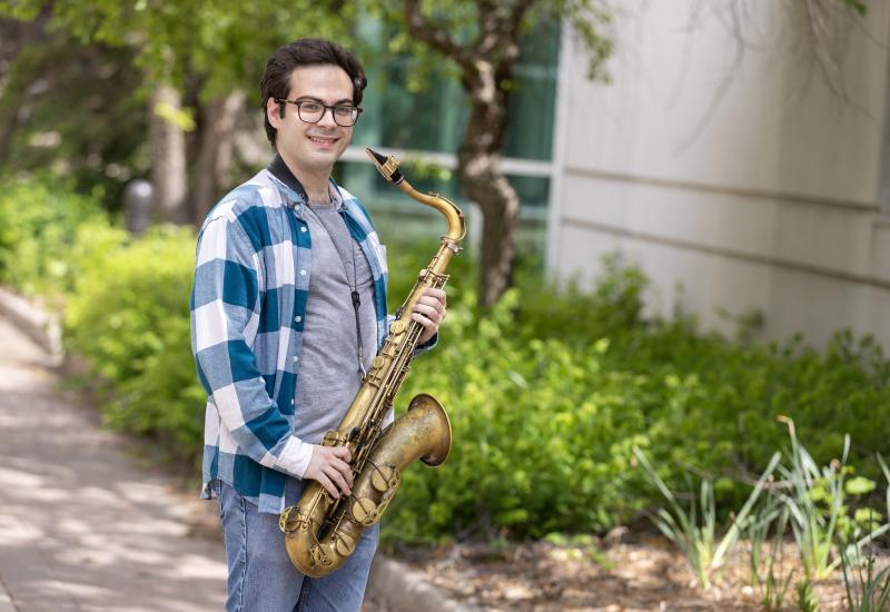 Eli Elder poses for a photo outdoors with his saxophone.