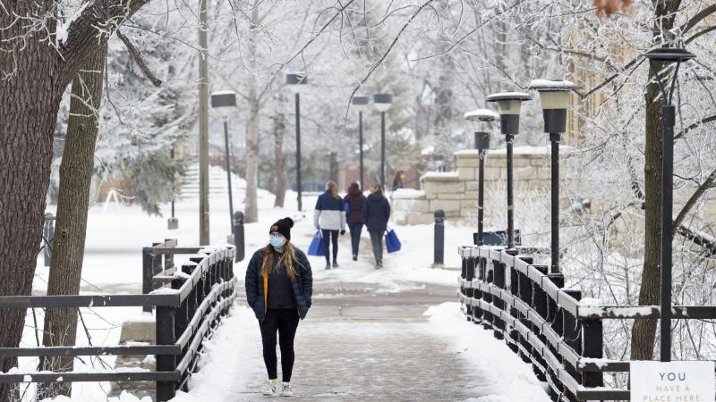 masked students crossing bridge in winter