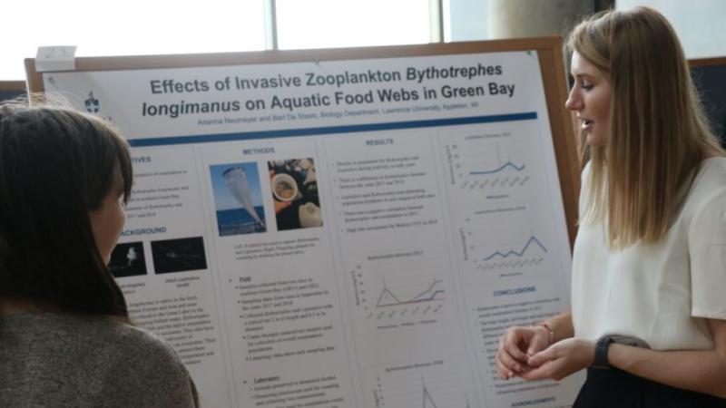 student looking at her poster while they present their research 