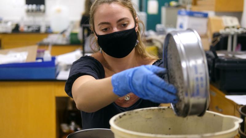 student sifting soil in a lab 