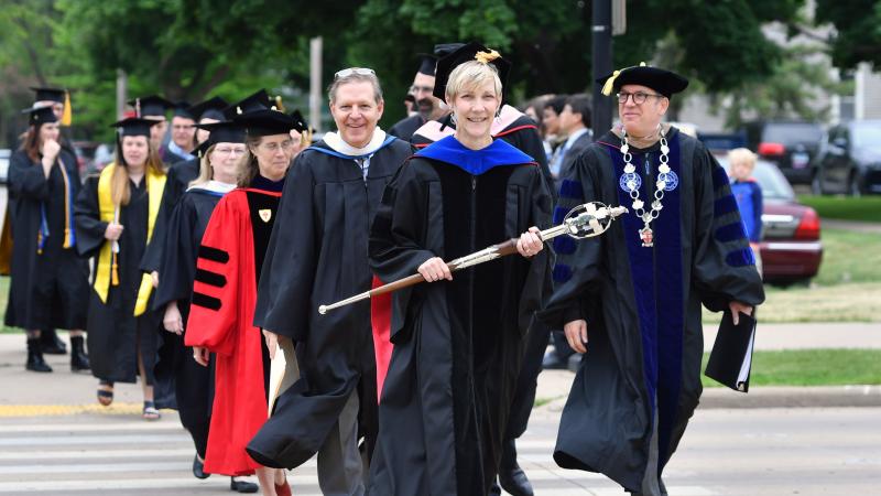 March across College Avenue to Main Hall green, led by Faculty Marshal Kathy Privatt and President Mark Burstein (right), part of Lawrence University’s Commencement