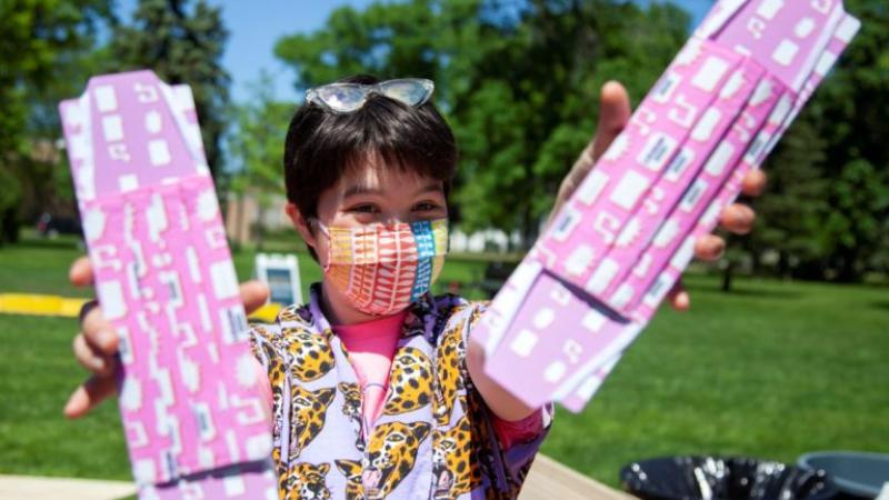 Georgia Greenberg holds up two pink masks featuring symbols from LUaroo.