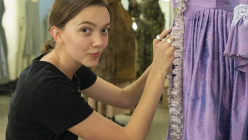 Mads Layton adjusts the stitching on an old-fashioned purple gown.